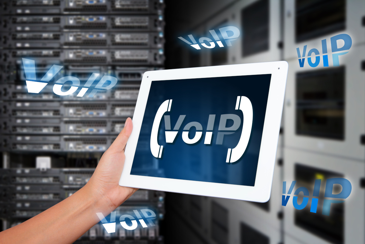 Hand Holding Tablet Displaying VoIP with Server Room Background